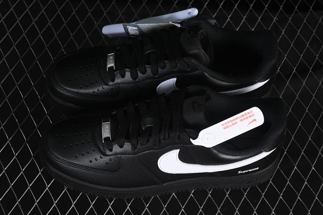 Pair of black low-top sneakers with white Swooshes and Supreme details