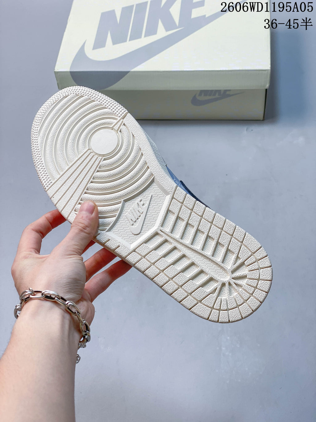 Textured outsole of a white sneaker shown beside a shoe box