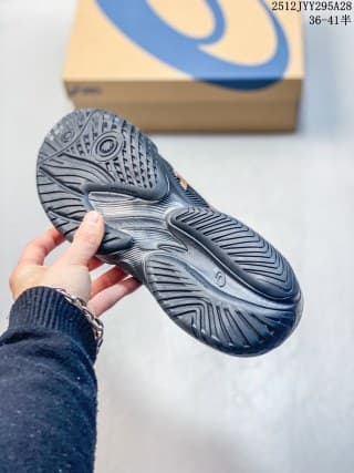 View of the dark navy ASICS sneaker outsole showing its textured traction pattern, with an ASICS shoebox in the background.