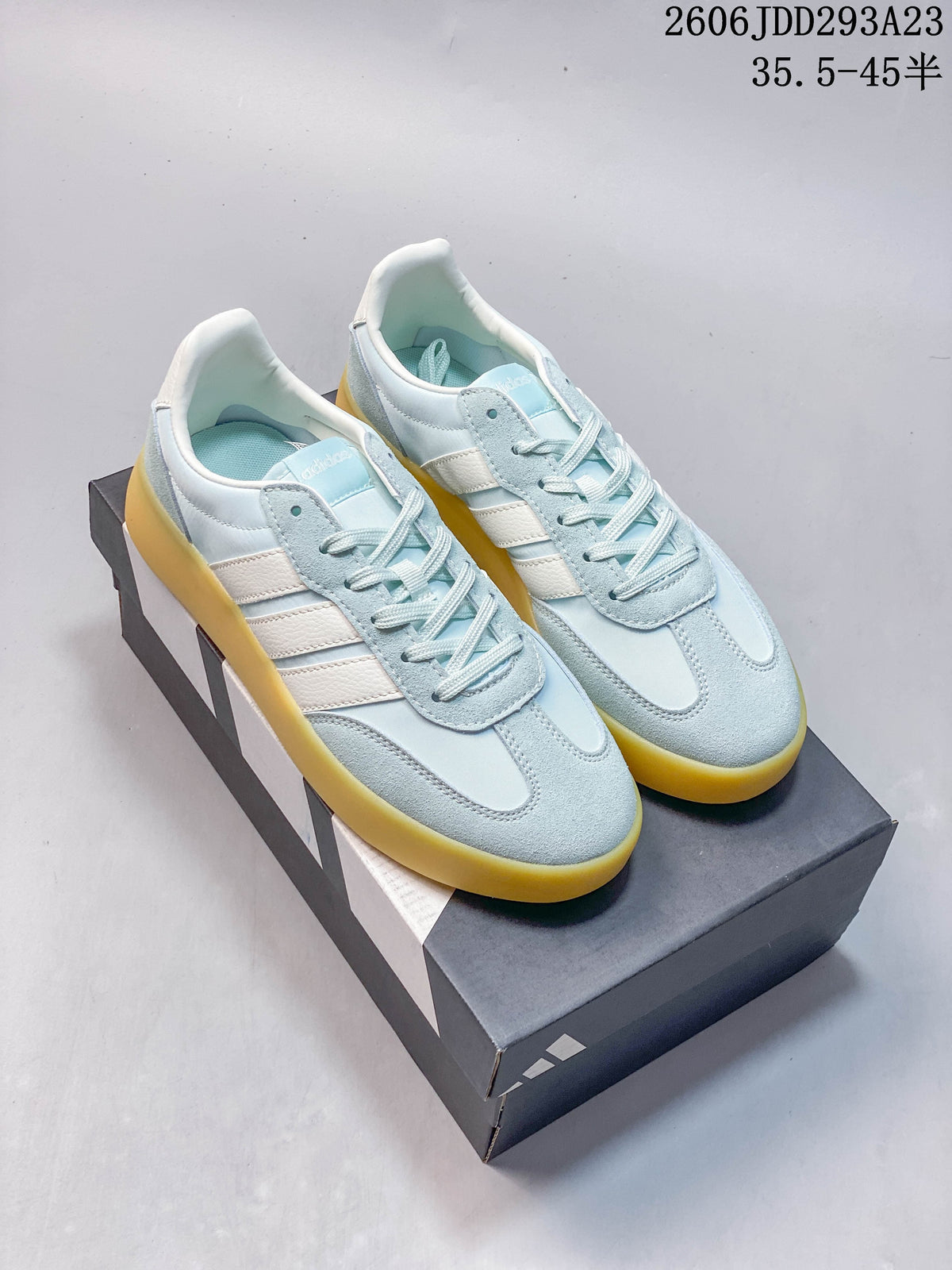 Pair of pale blue Adidas Barreda Decode sneakers with white stripes and a yellow-toned sole.