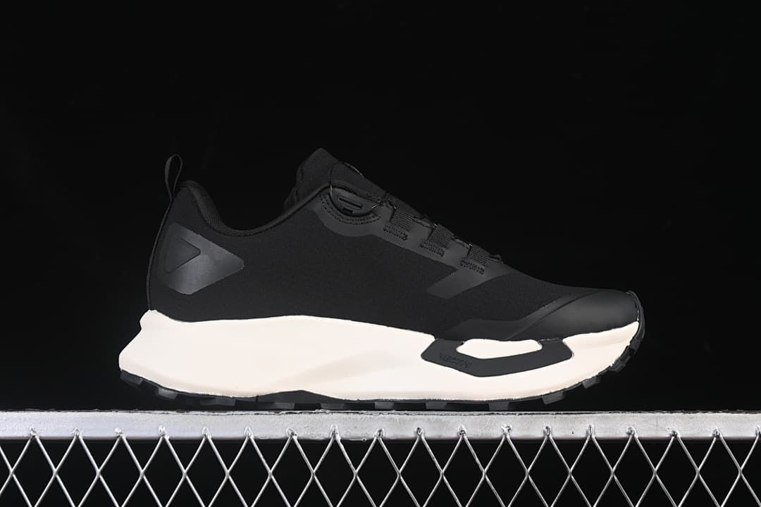 Side profile of a black shoe with a contrasting light-colored midsole.