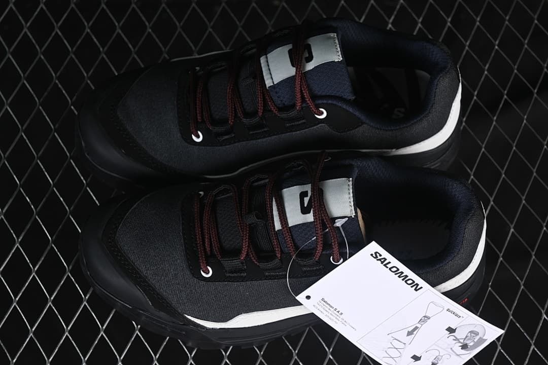 Pair of black and white Salomon shoes viewed from above beside a product tag.