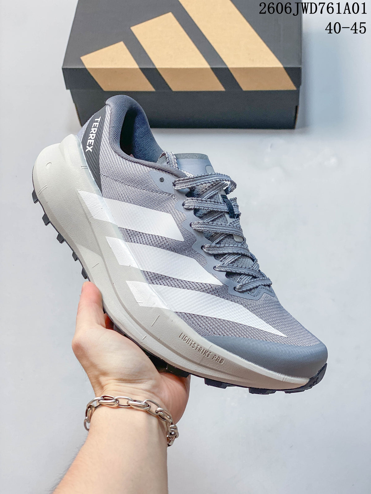 Gray Adidas Terrex trail running shoe with white stripes and a thick light-colored midsole