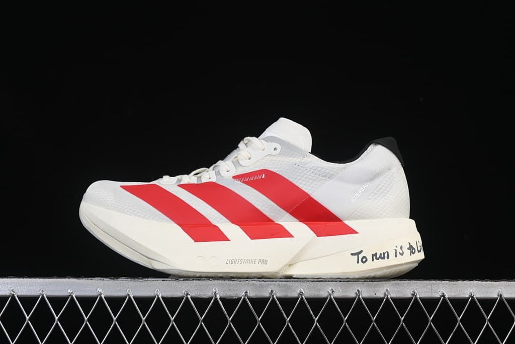 Side view of a white adidas Adizero running shoe with red stripes and Grete Waitz heel lettering
