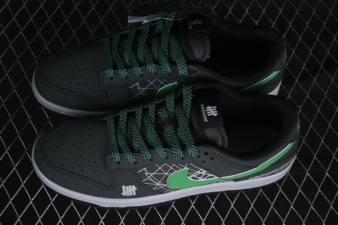 Overhead view of a pair of black low-top sneakers with green-and-black patterned laces and green Swooshes