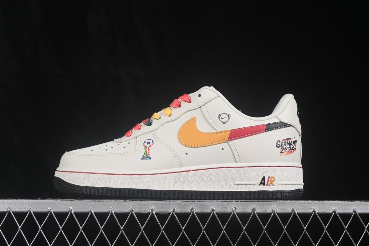 Side view of the white sneaker with orange, red, and black Swoosh detailing and Germany 2026 heel graphics.
