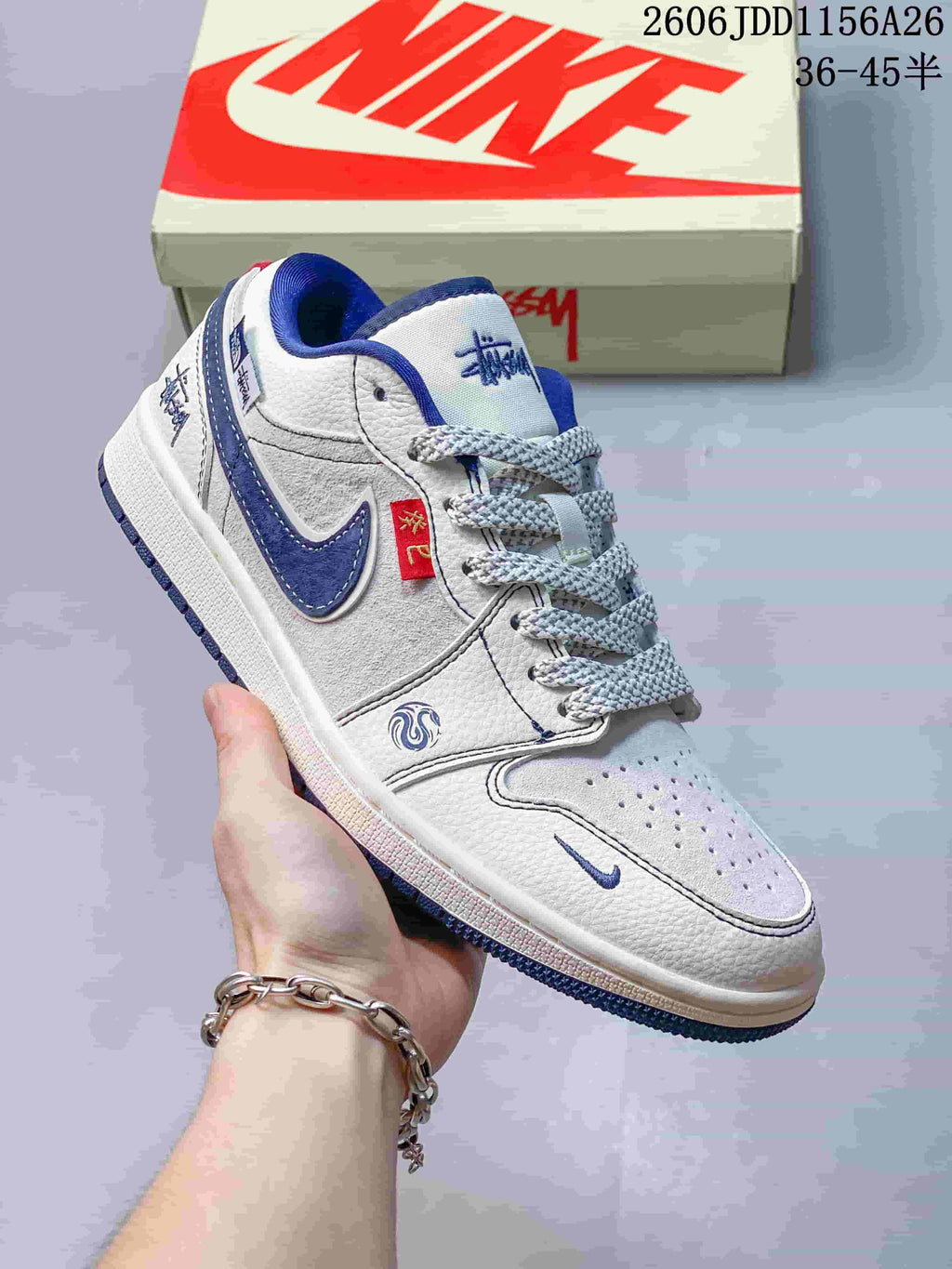 Close view of a white low-top sneaker with blue overlays, contrast stitching and perforated toe.