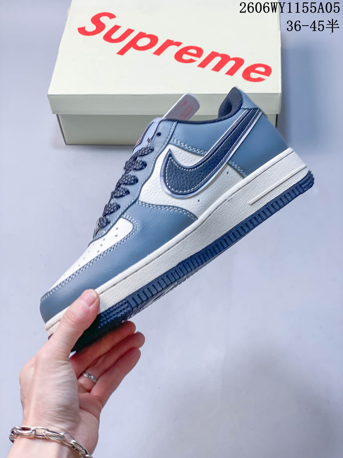 Side view of the low-top sneaker with white and blue panels, dark Swoosh and red accent.