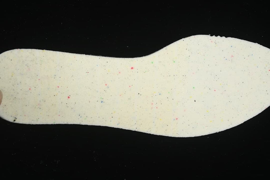 Close-up of a light-colored shoe insole with scattered colored flecks