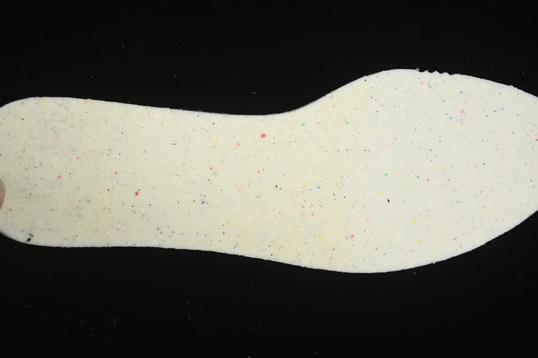 Close-up of a light-colored shoe insole with scattered colored flecks