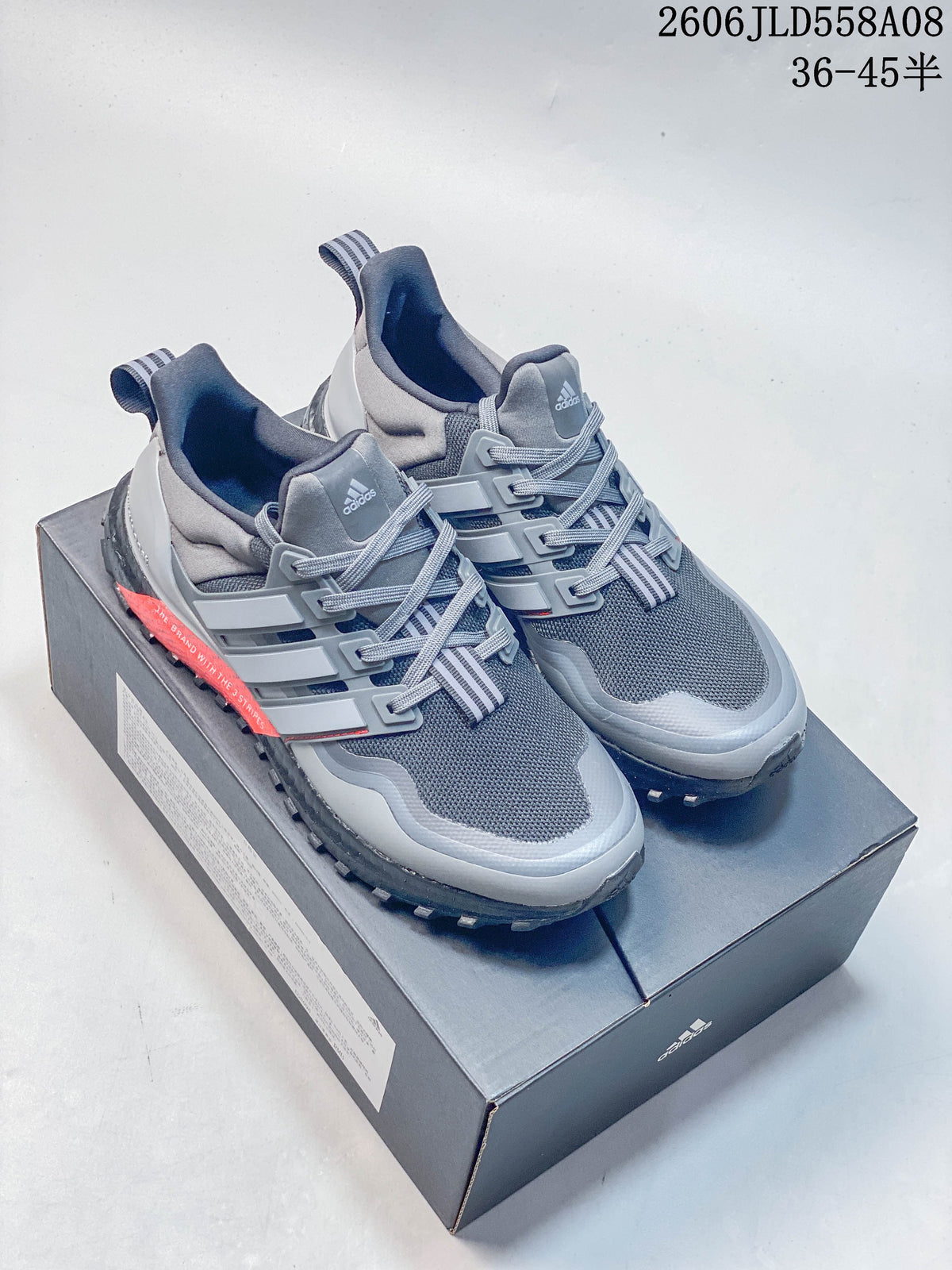 Pair of grey adidas UltraBOOST-style sneakers on a shoebox, viewed from above and the front.