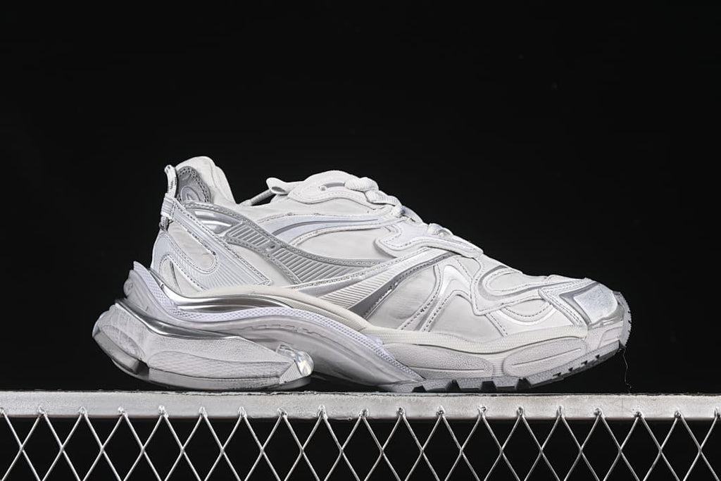 Side profile of the grey and silver sneaker with a sculpted sole.