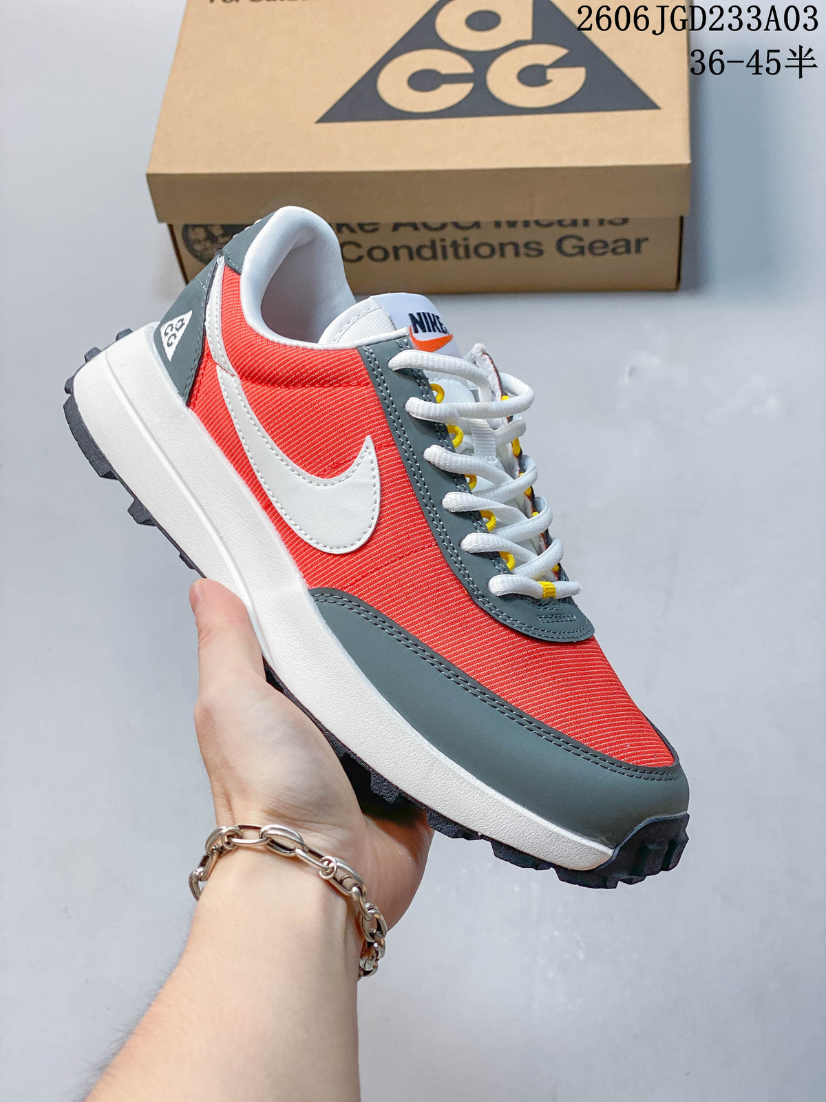 Side view of a red and gray Nike ACG low-top sneaker