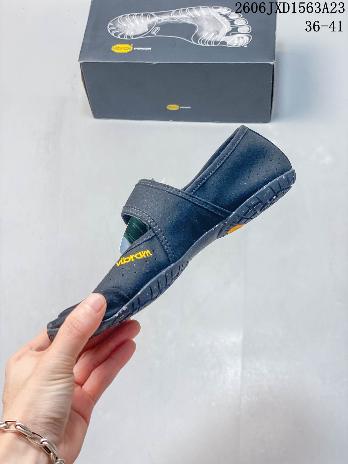Side view of a gray FiveFingers-style shoe with perforations and an adjustable strap