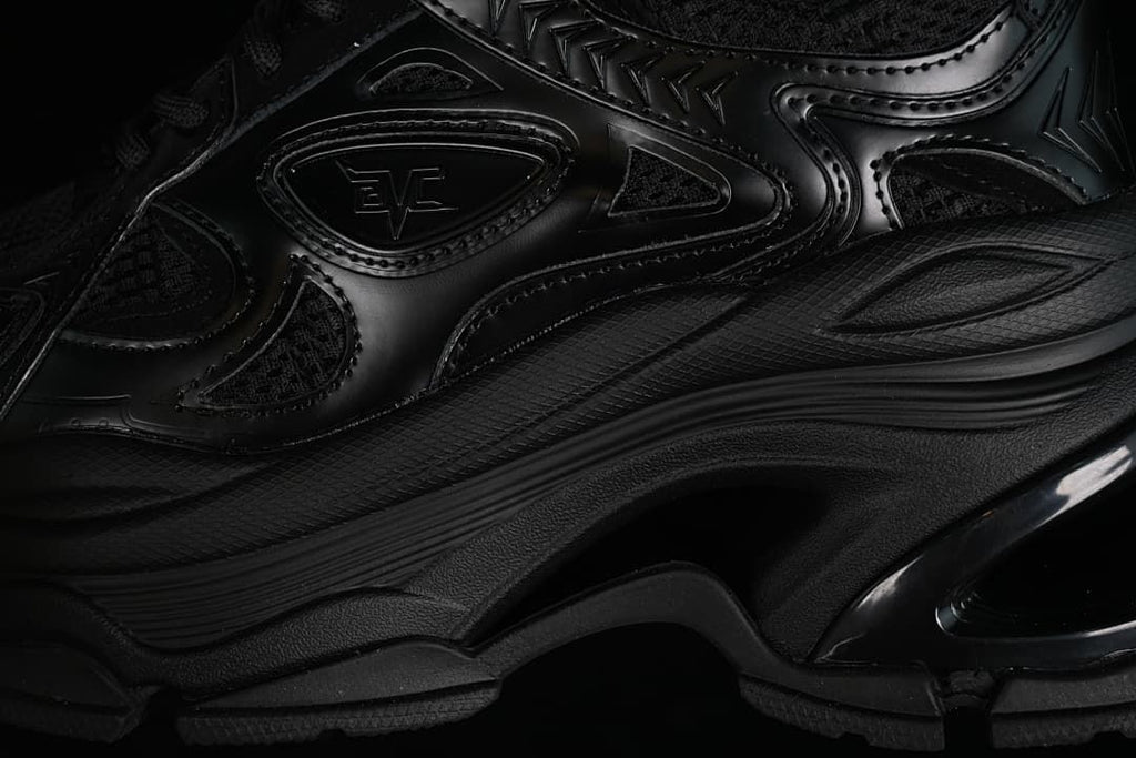 Close-up of the black sneaker's layered side panels and chunky sole.