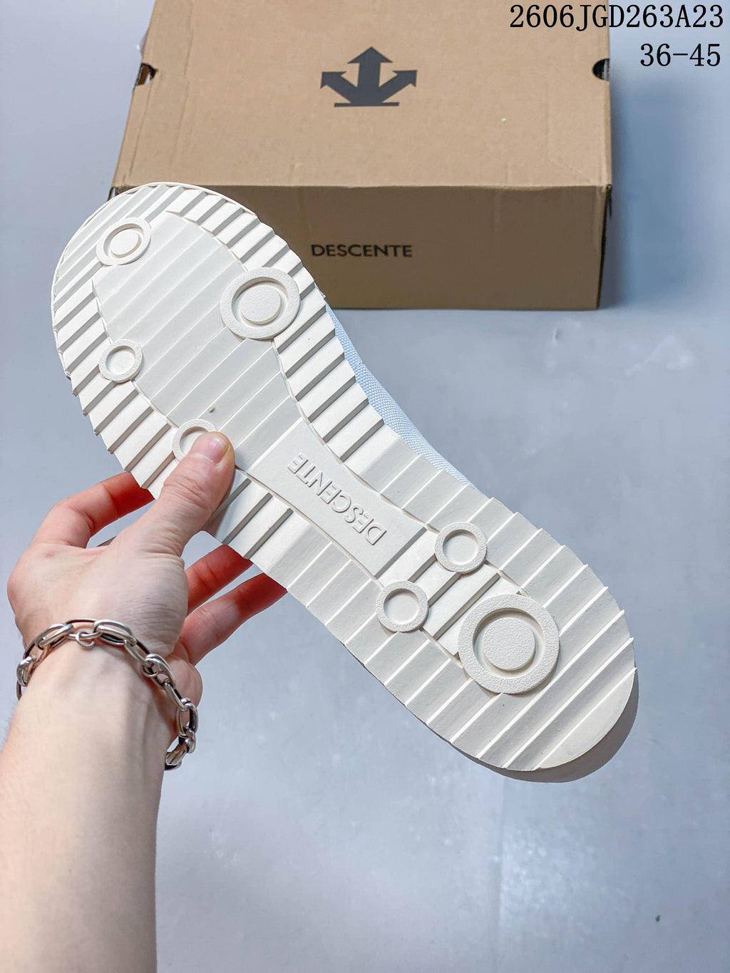 Underside of the white DESCENTE sneaker showing its ridged outsole