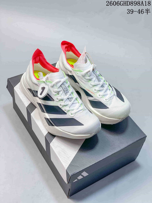 Pair of white Adidas Adizero running shoes with dark side stripes, red heel lining, and lime accents, displayed on a shoebox.