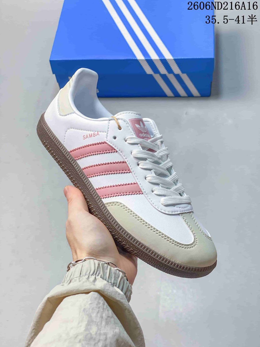 Angled side view of a white low-top sneaker with pink stripes and a gum-toned outsole
