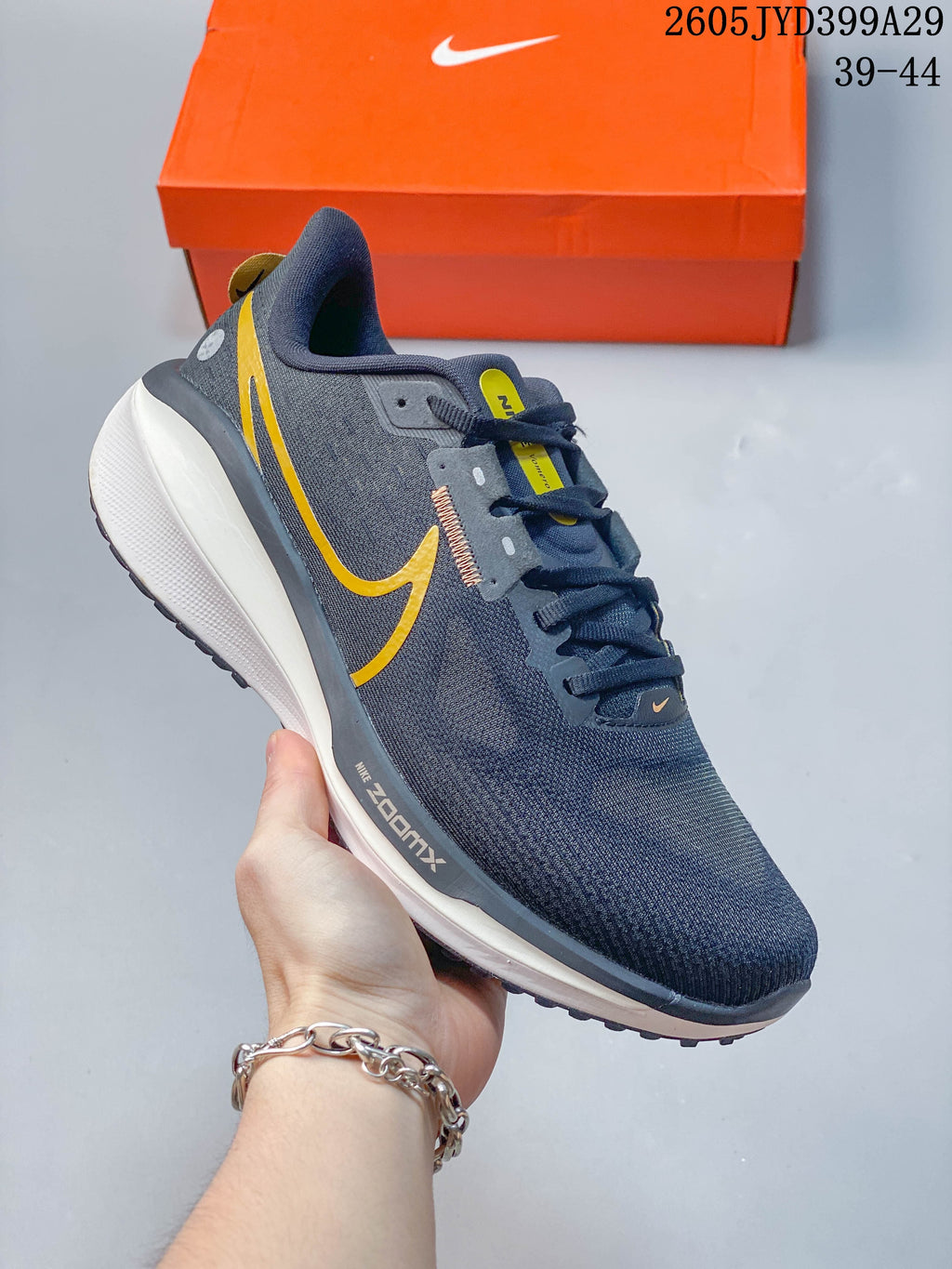 Angled side view of a dark gray Nike running shoe with yellow accents and a white midsole.
