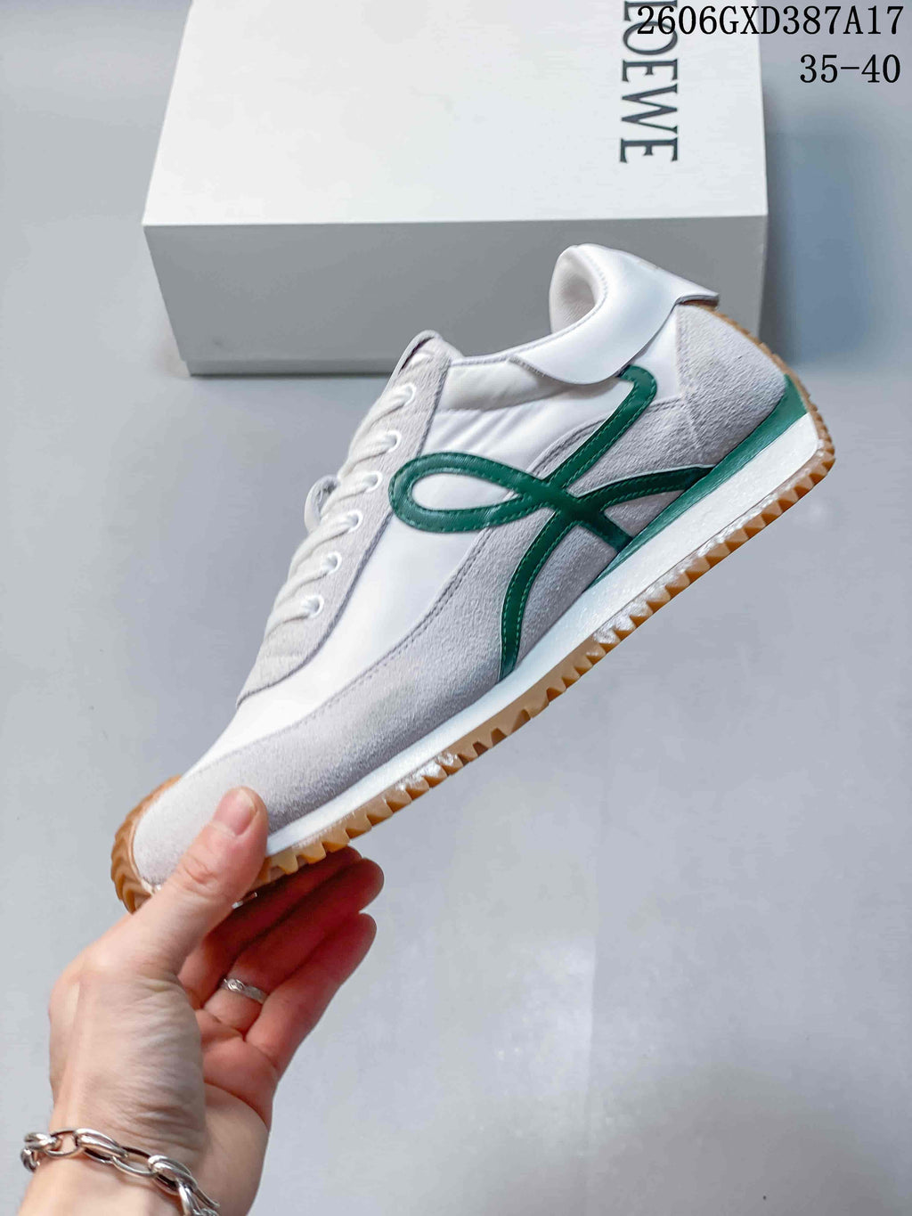 Side view of a sneaker with green detailing, light gray panels, and a gum-colored outsole