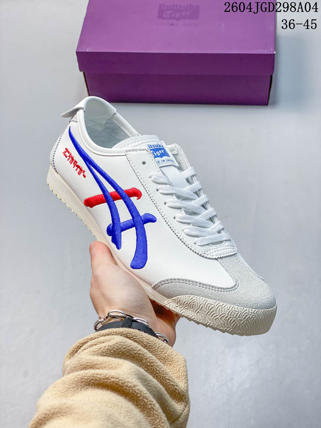 Close side view of the white sneaker with blue and red detailing and gray toe panels