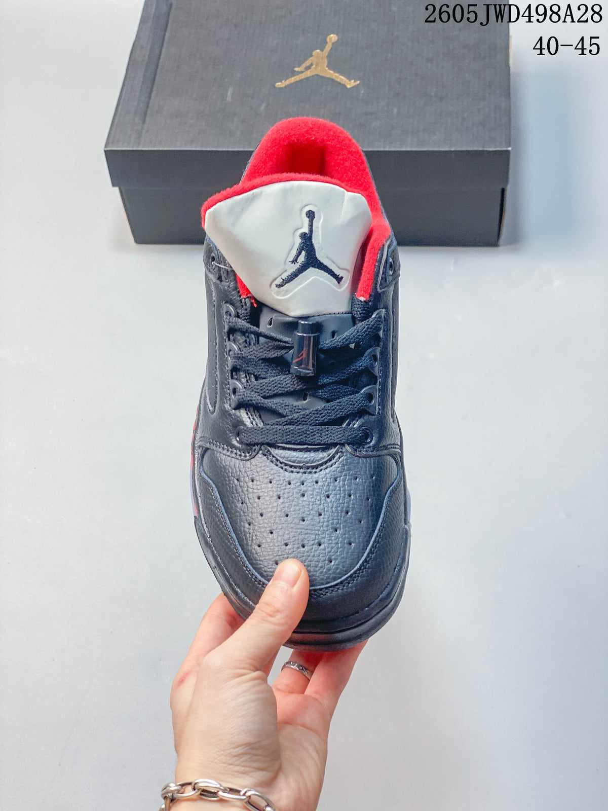 Front view of a dark Jordan sneaker with a light tongue, red lining and dark laces.