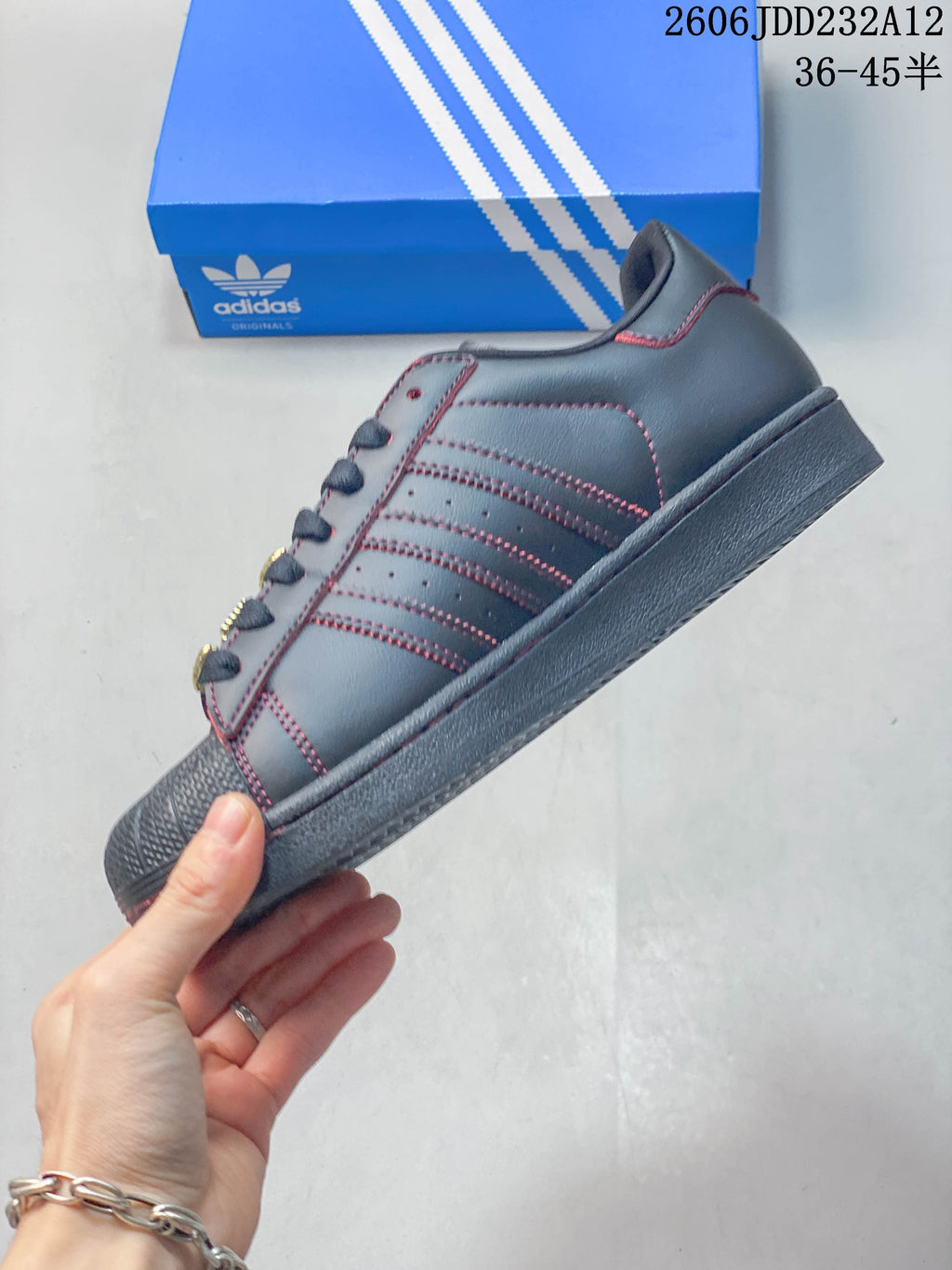 Side profile showing the charcoal upper, red contrast stitching, three side stripes, and flat outsole.