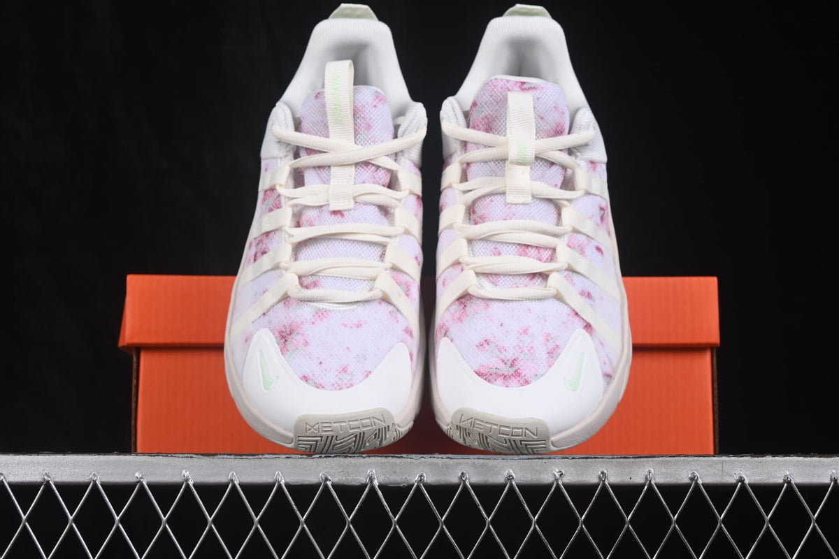 Pair of Nike Free Metcon 7 sneakers viewed from the front, showing white uppers with pink patterned panels and light mint accents.