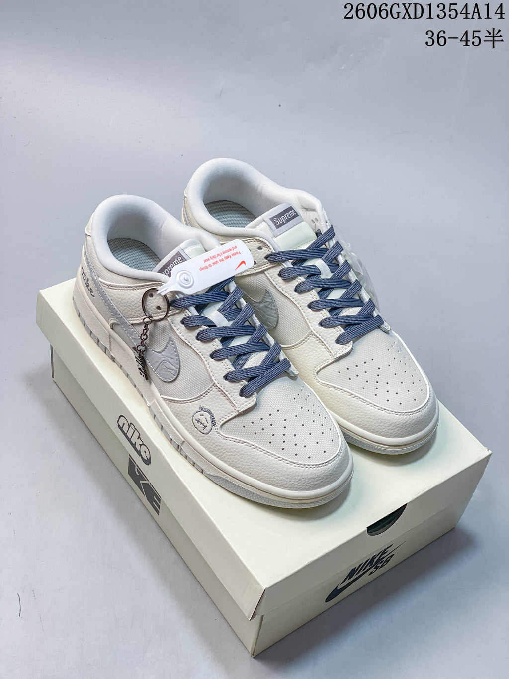 Off-white Nike Dunk Low sneakers with navy laces, embroidered details and a shoe box