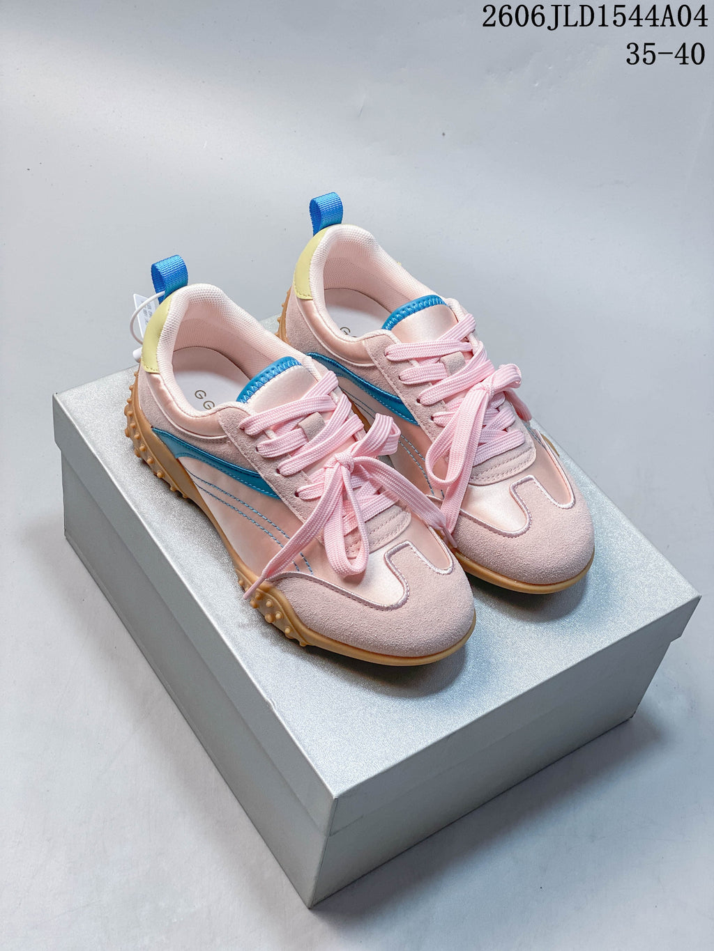 Pair of pale pink low-top sneakers with blue side stripes, yellow heel accents, pink laces, and tan nubbed soles.