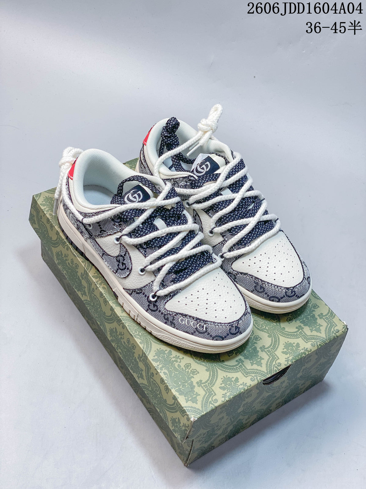 Pair of cream and navy patterned Nike SB Dunk Low sneakers on a decorative green box
