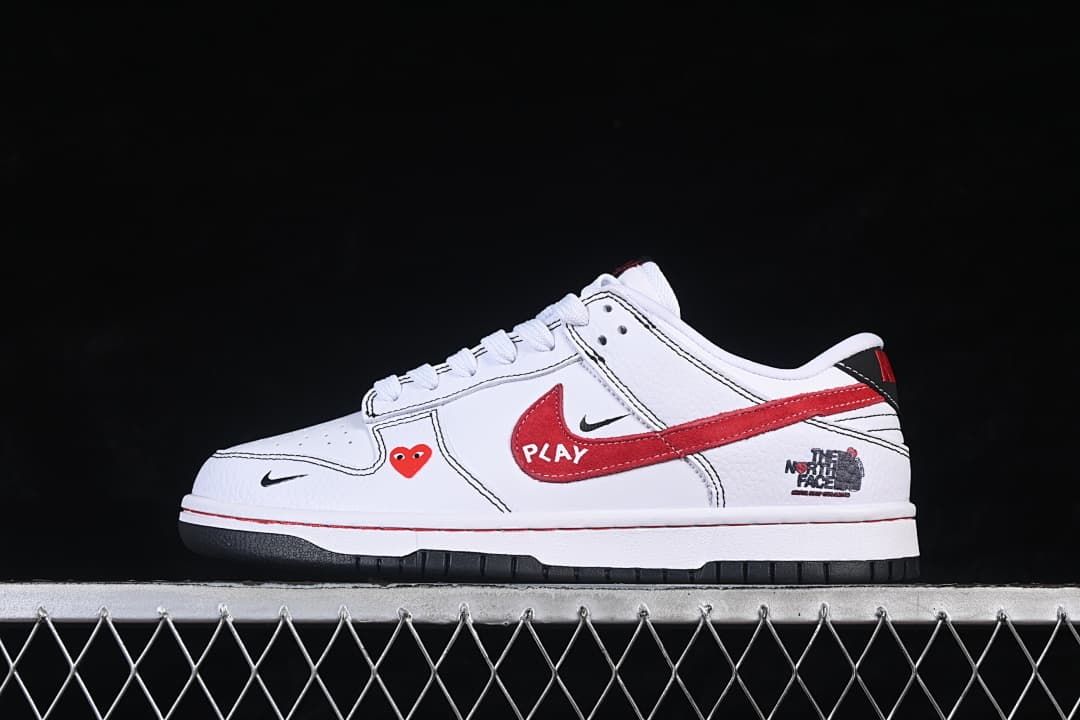 Side view of a white low-top sneaker with red and black graphic details and a dark outsole.
