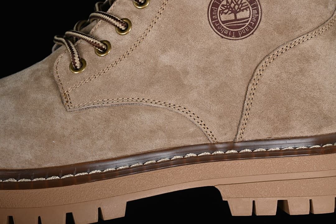 Close-up of the khaki boot upper, stitching, side emblem, laces, and lugged sole.