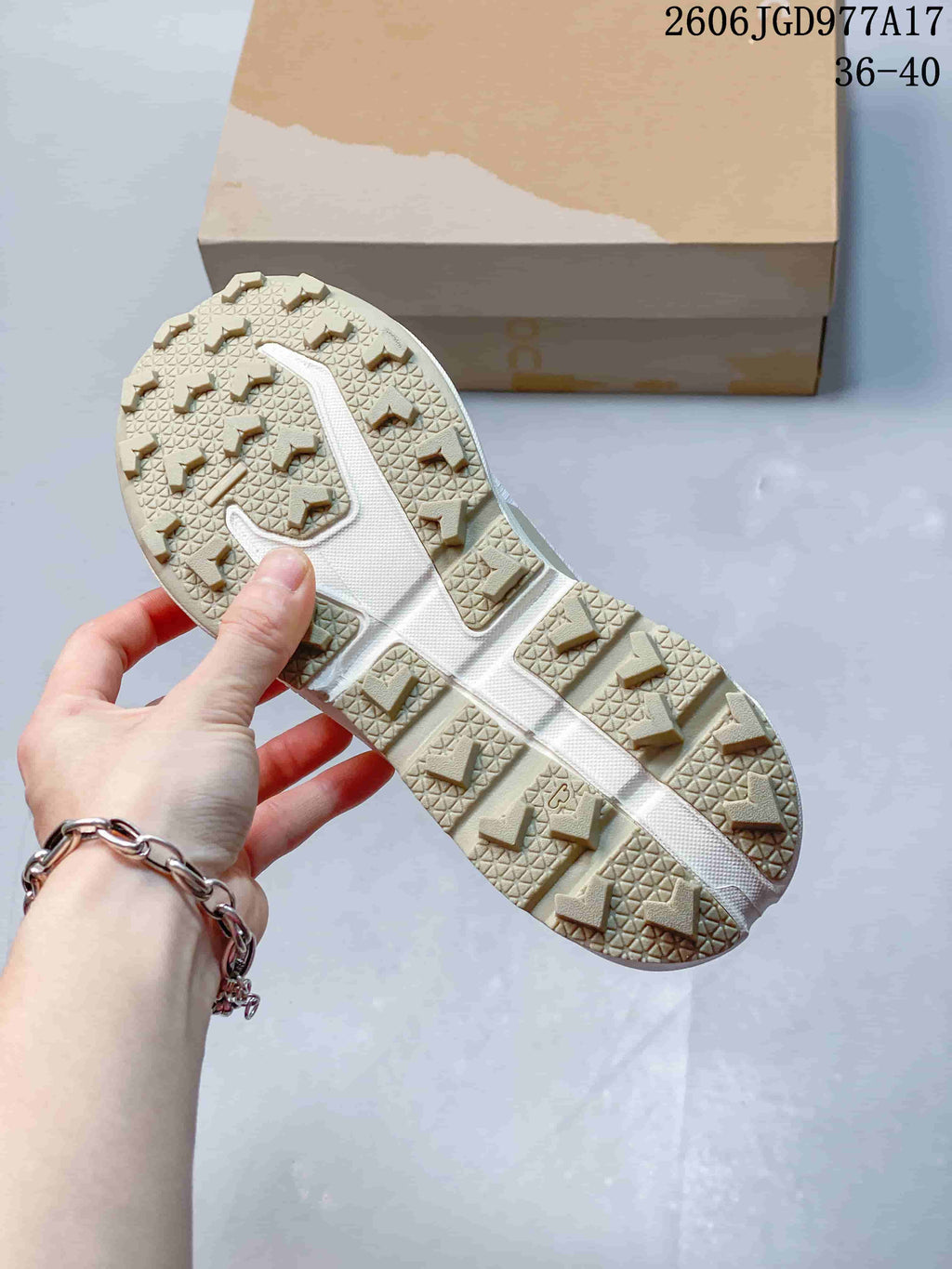Close-up of the lugged outsole on a white and pink trail shoe.