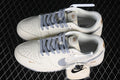 Pair of off-white Nike SB Dunk Low sneakers with grey laces and Swooshes, gold-tone details, and extra laces.
