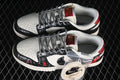 Pair of black-and-white low-top sneakers with red details and an additional pair of light-colored laces.