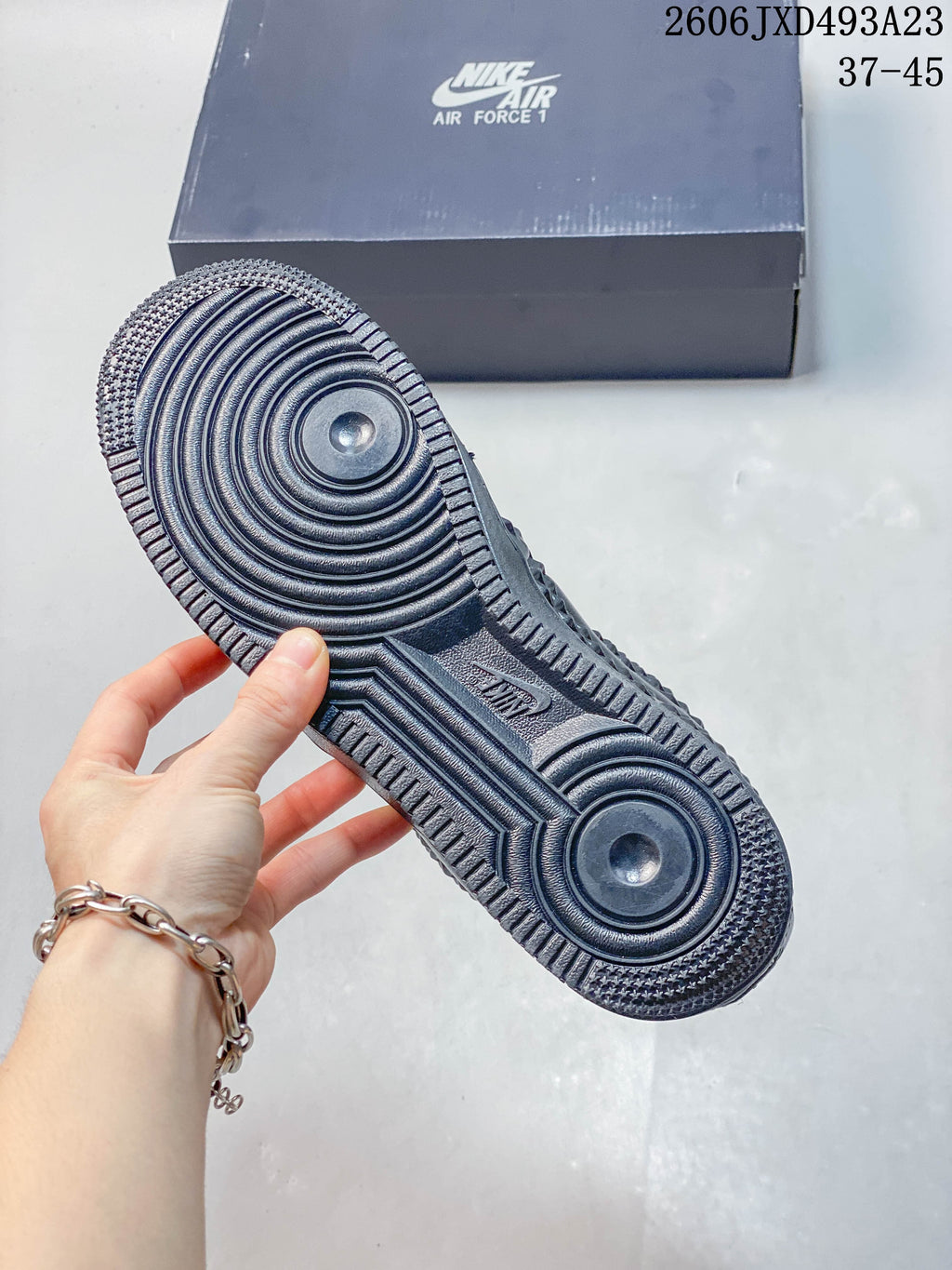 Underside of a dark sneaker showing circular outsole patterns and textured tread