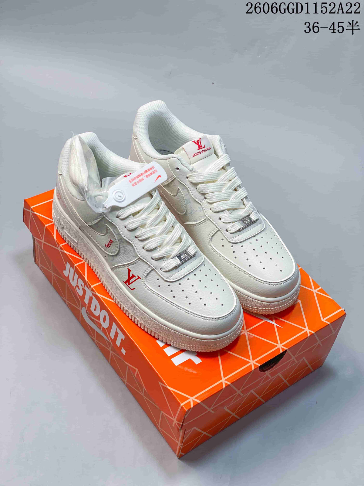 Pair of white low-top sneakers with textured panels, red accents and monogram-style detailing