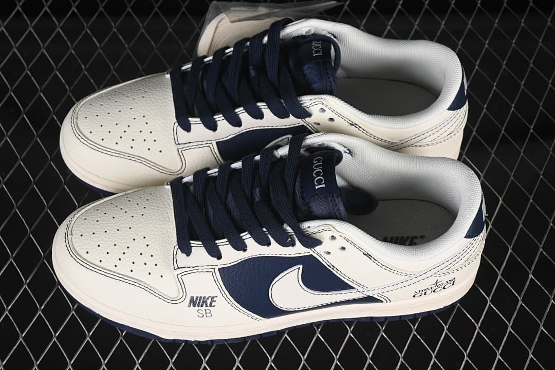 Top view of a pair of off-white and navy low-top sneakers with perforated toes and navy laces.