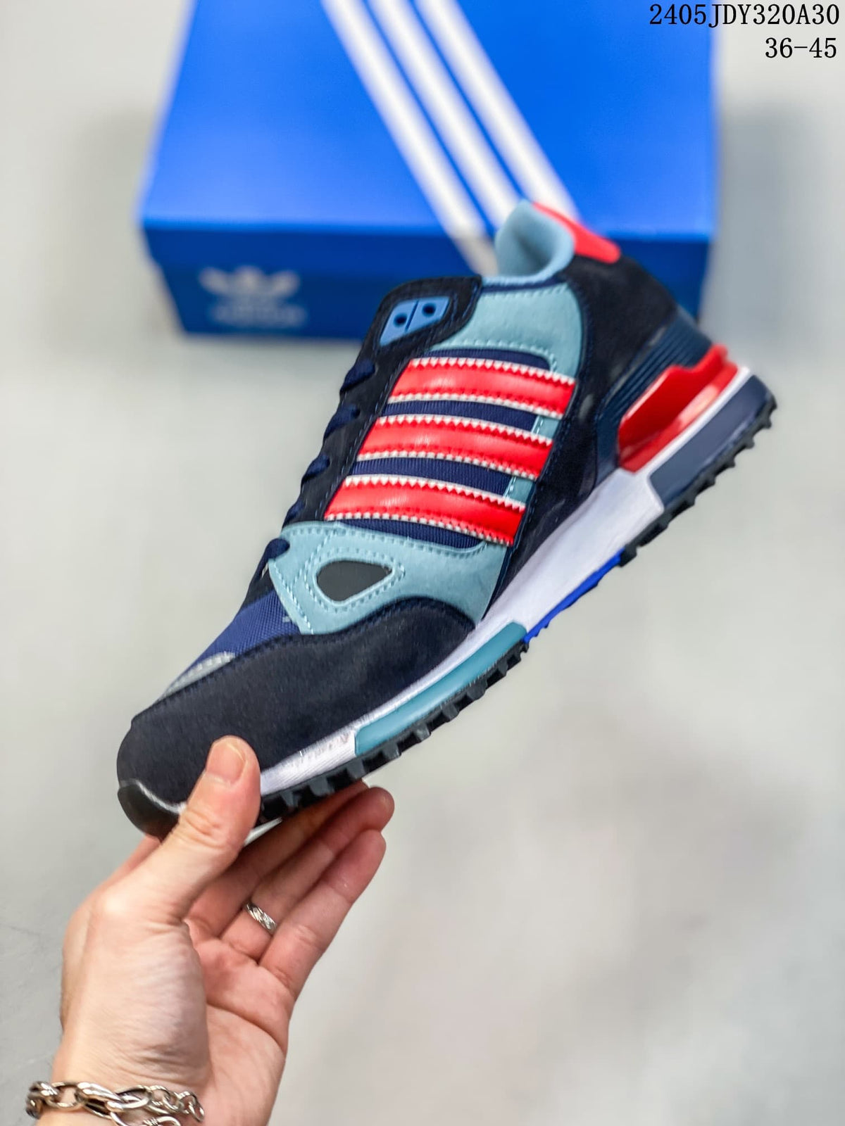 Side view of the Adidas ZX 750 with navy, light blue, and red panels and three side stripes.