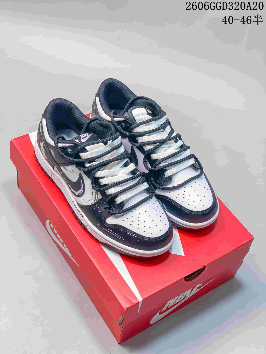 Pair of black, white, and gray Nike Dunk Low Retro sneakers on a red shoe box