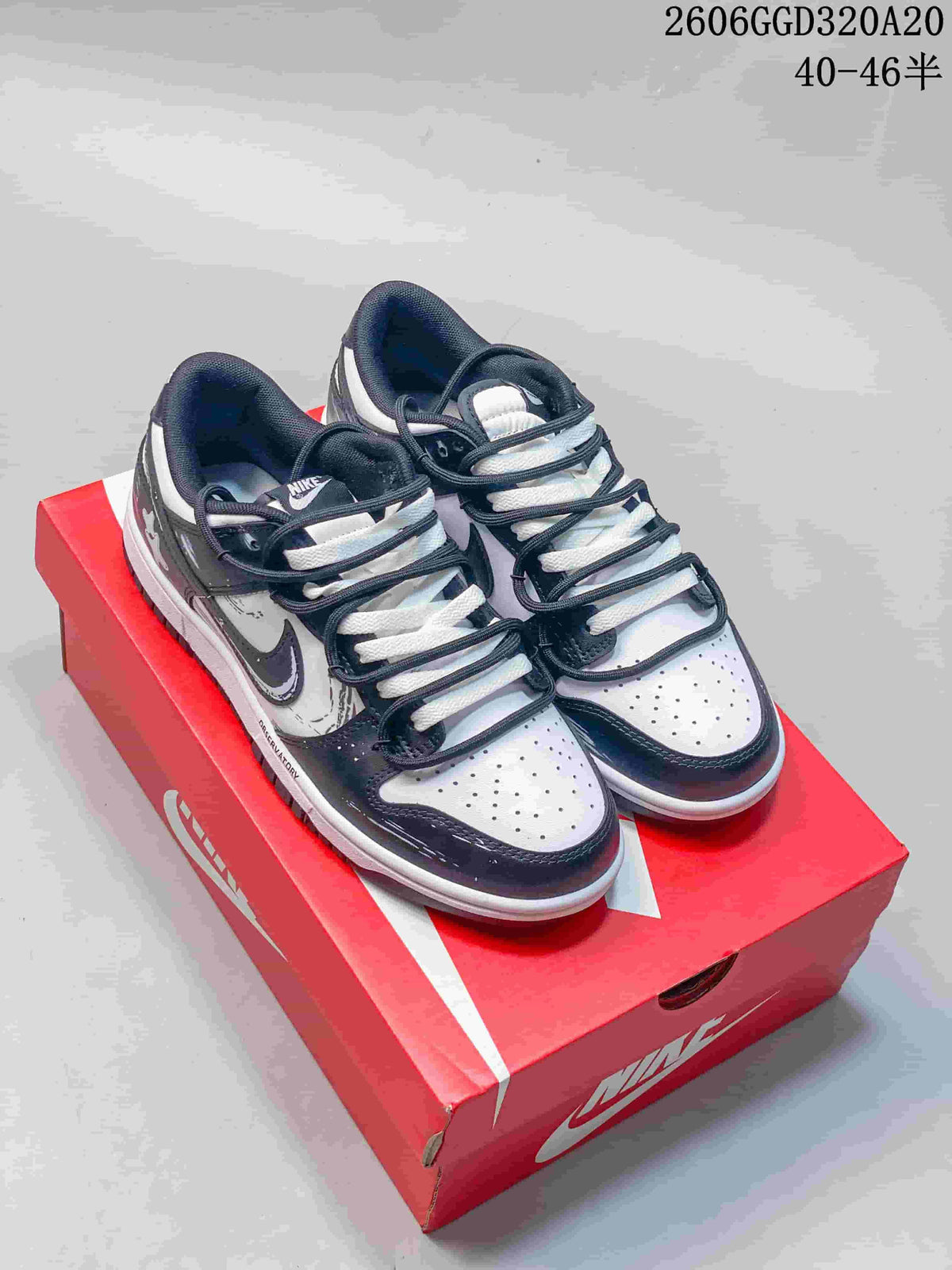 Pair of black, white, and gray Nike Dunk Low Retro sneakers on a red shoe box