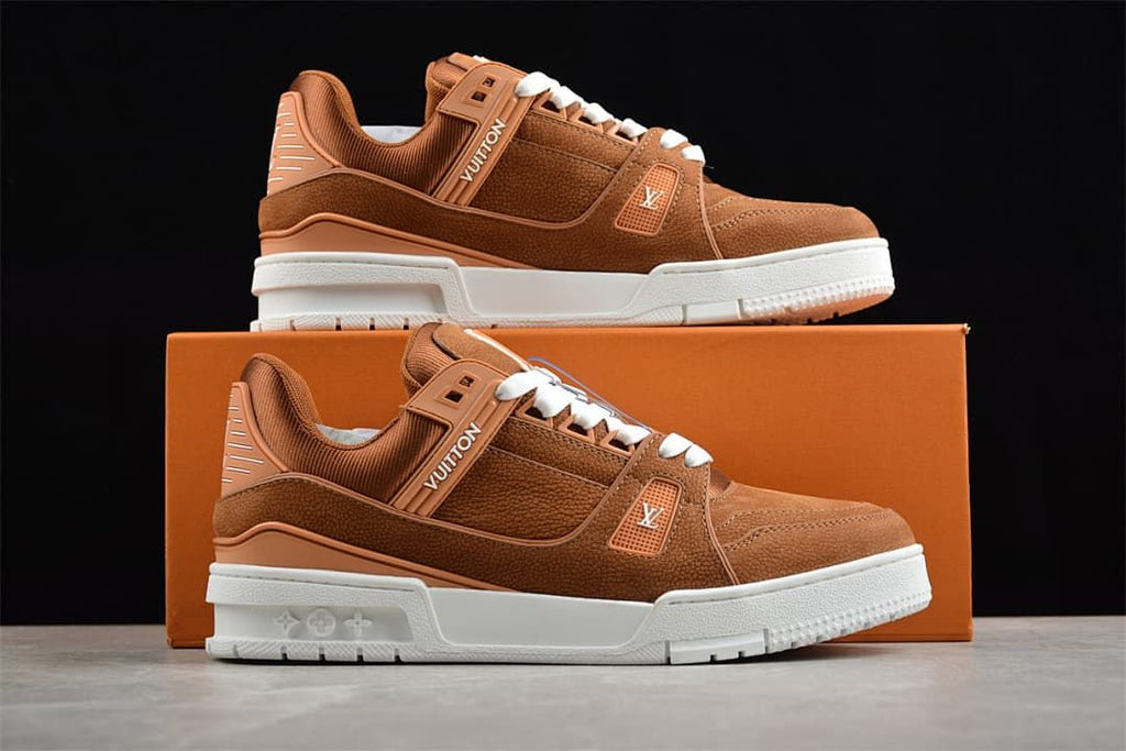 Two brown LV Trainer sneakers displayed on and beside a shoe box