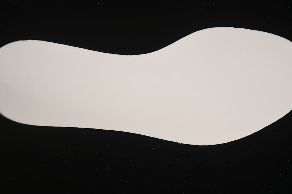 Light-colored shoe insole shown against a dark background