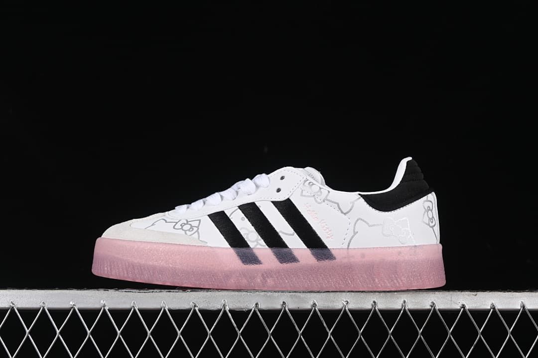 Side view of white adidas Samba W sneakers with black stripes, Hello Kitty graphics, and a pink sole.