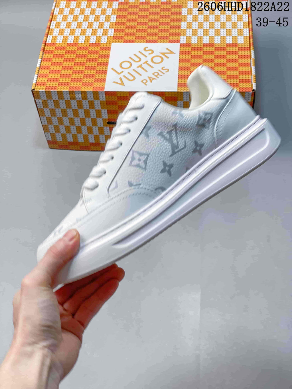 Side view of a white low-top sneaker with multicolored monogram-style patterning and a thick sole
