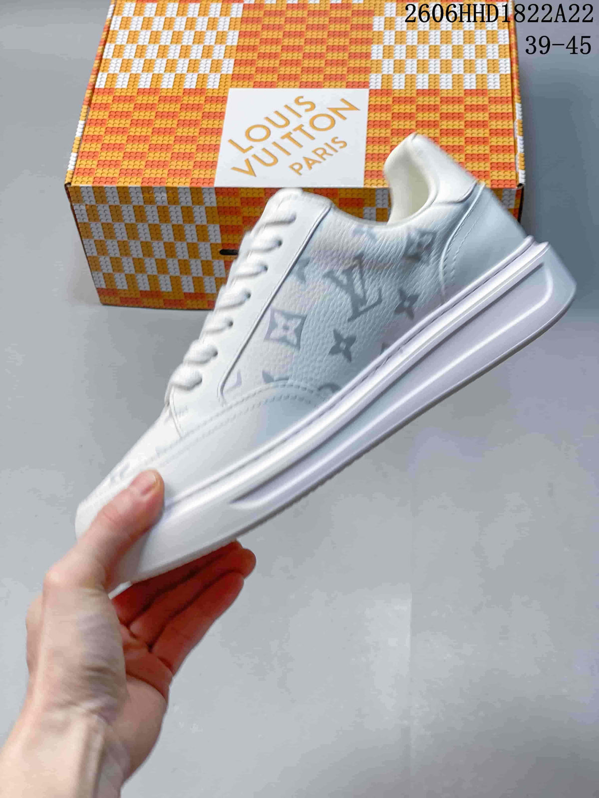 Side view of a white low-top sneaker with multicolored monogram-style patterning and a thick sole