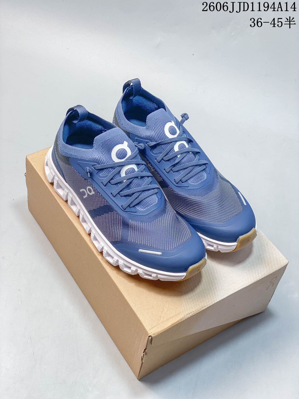 Pair of blue On Cloud 6 Versa sneakers with white segmented outsoles, displayed on a shoe box.