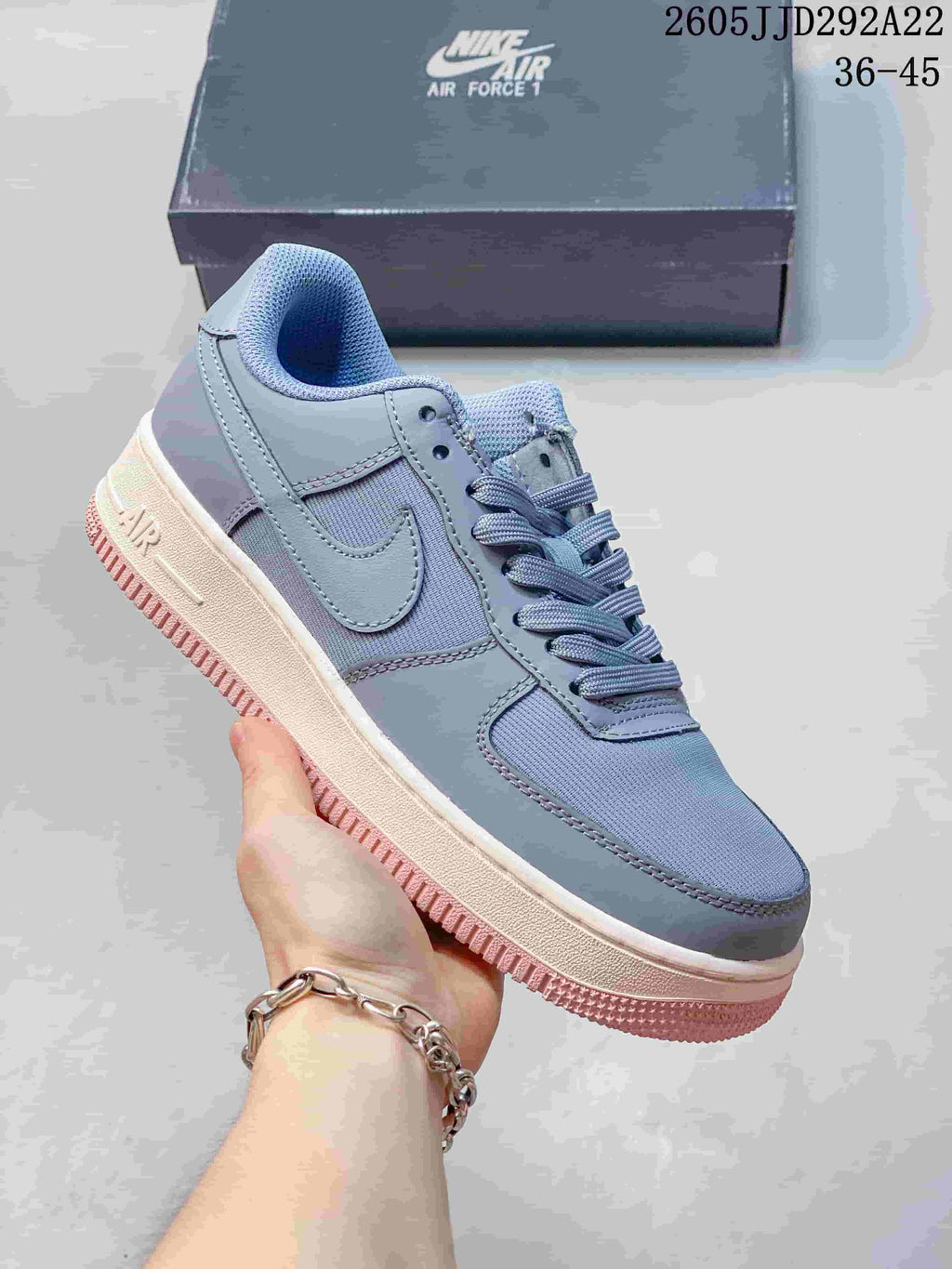 Blue-gray low-top sneaker with layered panels and a cream and pink outsole.