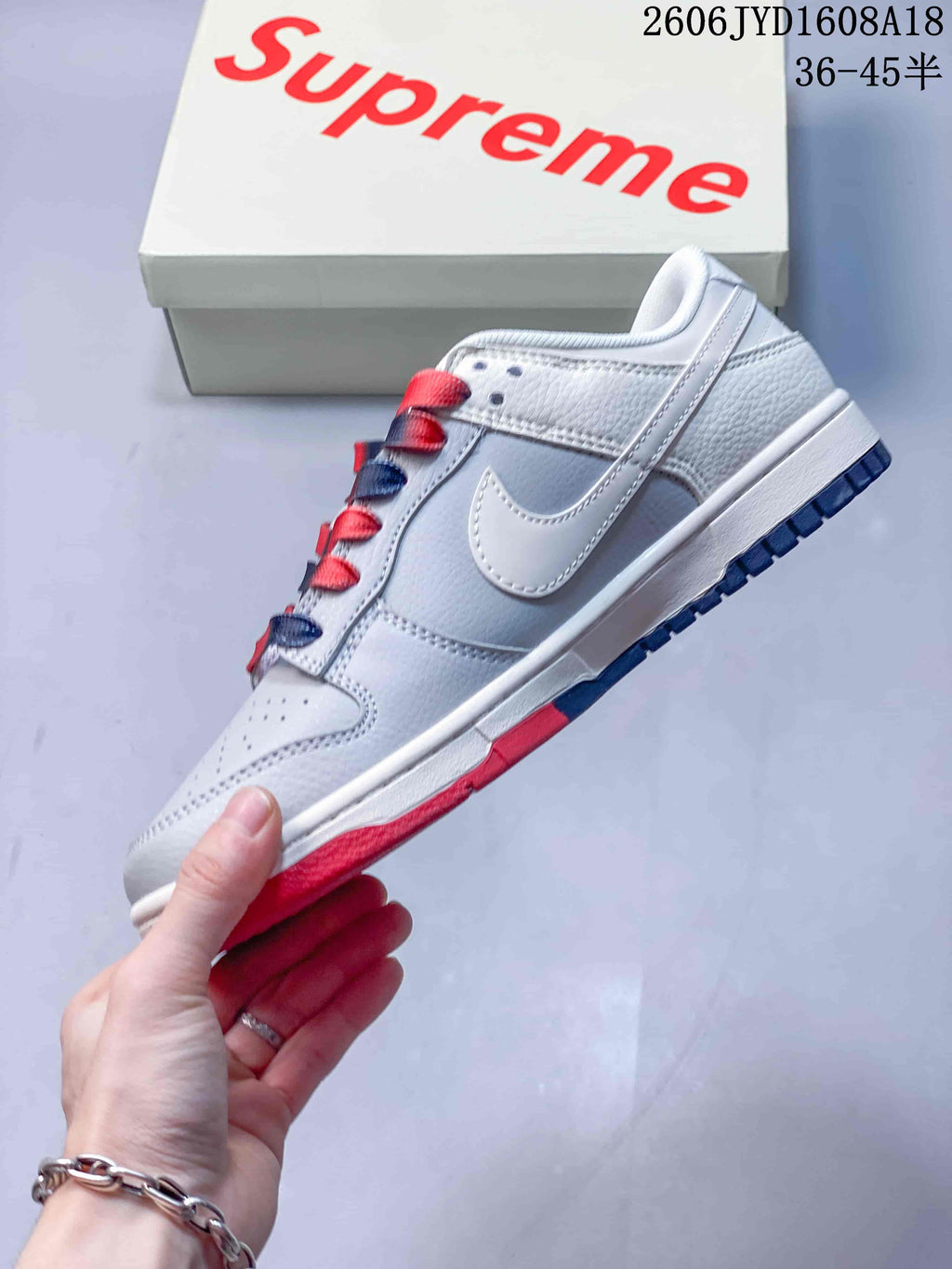 Side view of the grey and white low-top sneaker with a white Swoosh and red outsole accents.